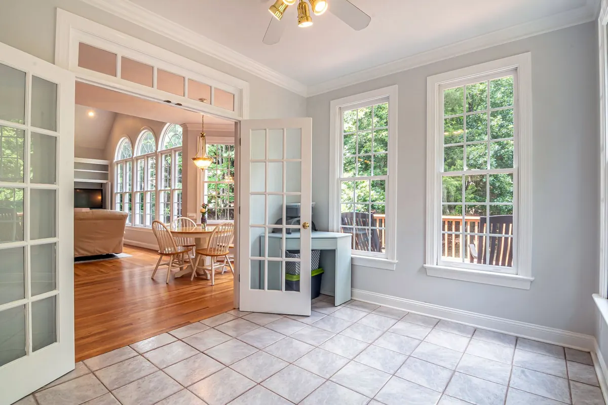White-framed glass French doors opening from a bright room onto a garden